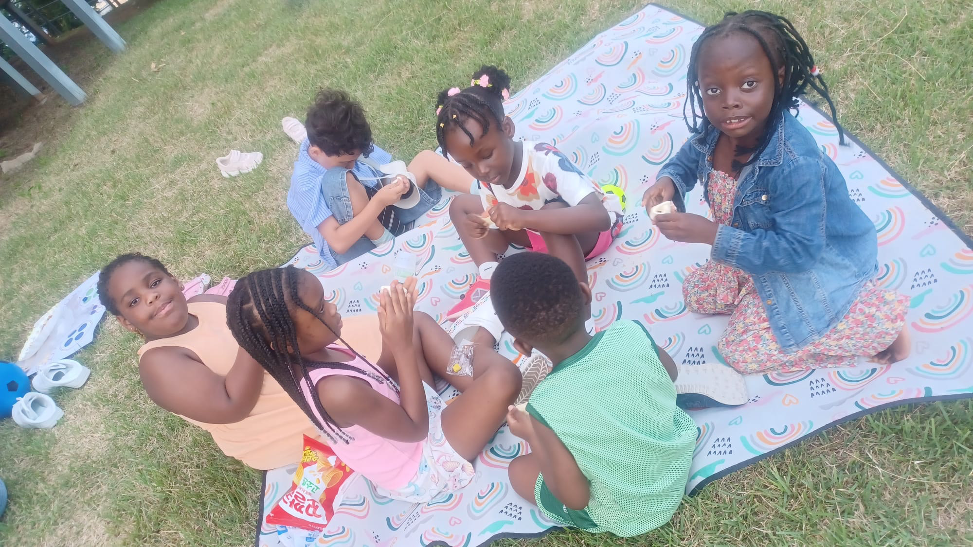 Children sharing snacks on a picnic blanket at the Songtan get-together