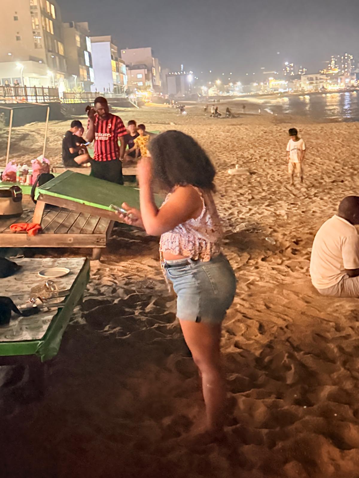 USKA members still on the sand at Bongpo Beach after dark, lights of the town along the water
